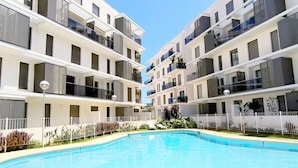 A modern apartment building with a swimming pool, balconies, and a clear sky. - Ático Marina Real III (Dénia)