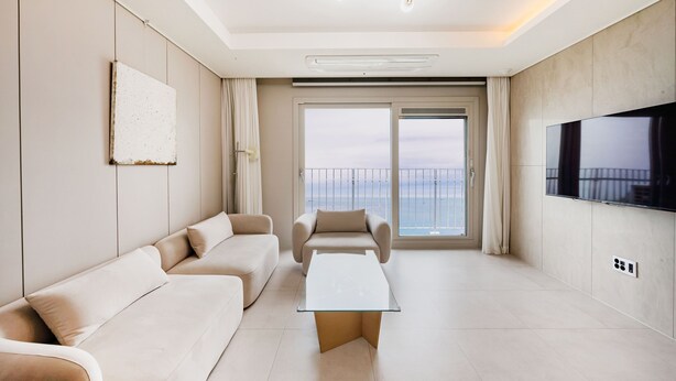 A modern living room with a sofa, a coffee table, and a TV. - Odays Osiria Residence (Busan)