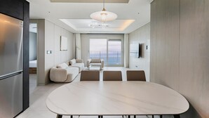 A modern living room with a large oval table, a sofa set, and a television mounted on the wall. - Odays Osiria Residence (Busan)