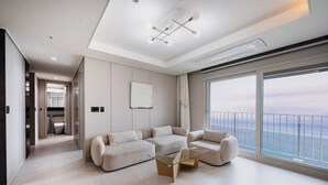A modern living room with a glass coffee table, two sofas, and a large window with a view of the sea. - Odays Osiria Residence (Busan)