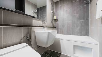 Une salle de bain moderne équipée de toilettes, d’un lavabo et d’une baignoire.