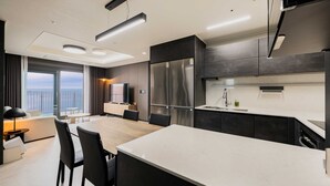 A modern kitchen with a large island, dark cabinetry, and stainless steel appliances. - Odays Osiria Residence (Busan)