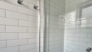 A modern bathroom with white subway tiles, a glass shower enclosure, and a black tiled floor.