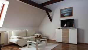 Ein modernes Wohnzimmer mit einem weißen Sofa, einem Glastisch, Holzboden, einem weißen Schrank und einem Gemälde an der Wand.
