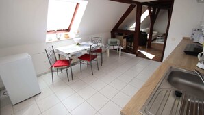 Eine Küche mit Esstisch, Stühlen, einem Kühlschrank, einem Fenster und einer Spüle.