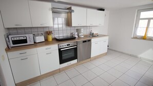 Eine moderne Küche mit weißen Schränken, einer Mikrowelle, einem Toaster, einer Kaffeemaschine und einem Geschirrspüler.