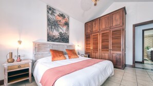 A bedroom with a large bed, wooden wardrobe, and a painting on the wall.