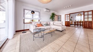 A spacious living room with a large sectional sofa, a coffee table, and a dining area with a wooden table and chairs.
