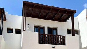 Un immeuble résidentiel à deux étages doté d’un balcon, d’une porte d’entrée et d’une boîte aux lettres.