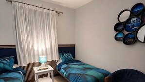 Une chambre avec deux lits, une table de chevet, une chaise, un tapis et un mur orné de miroirs ronds.