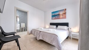 A bedroom with a bed, bedside tables, a chair, and a painting on the wall.