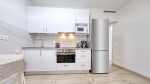 A modern kitchen with white cabinets, a built-in oven, a microwave, and a refrigerator.