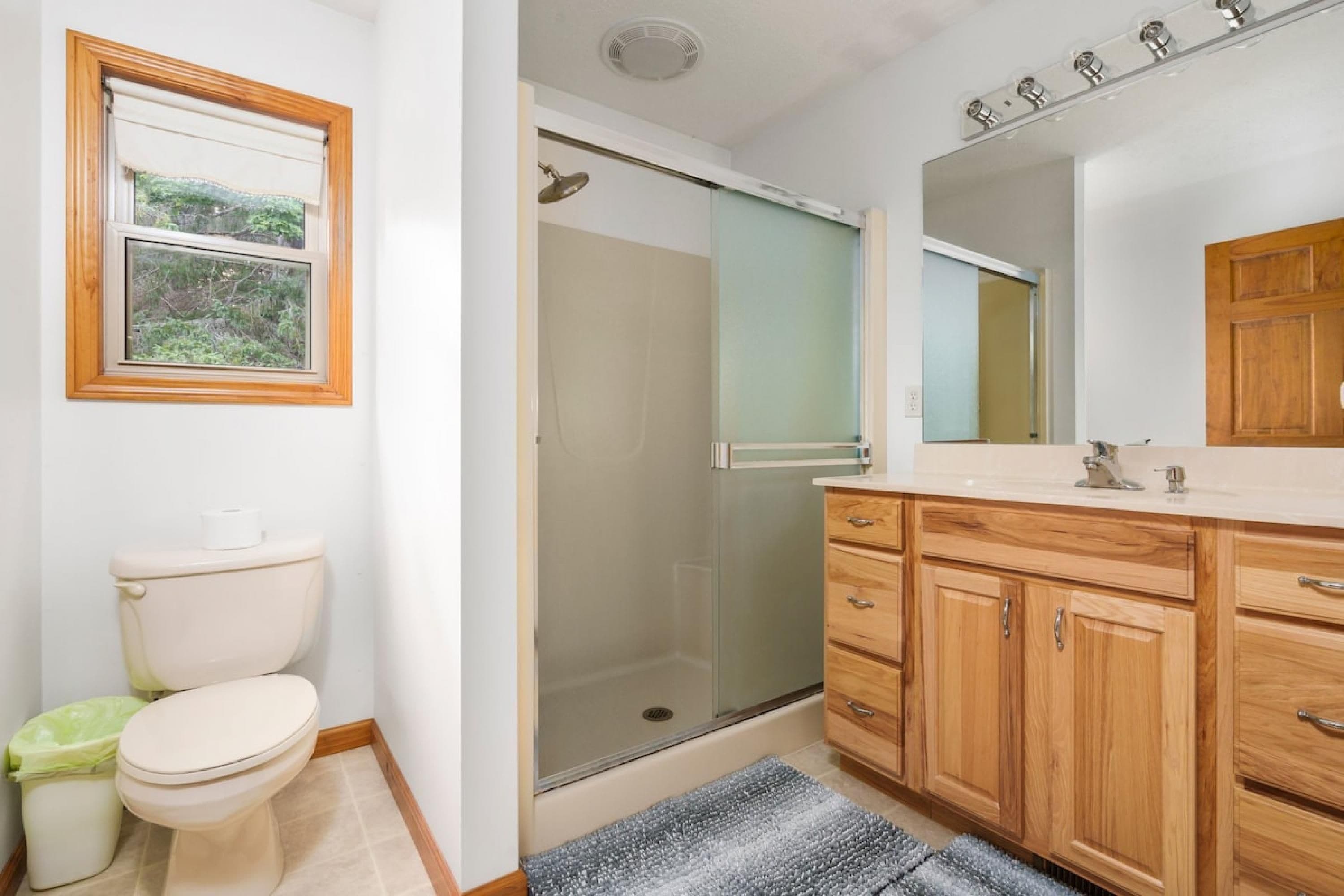 Ein Badezimmer mit Toilette, Dusche, Waschtisch und Fenster.