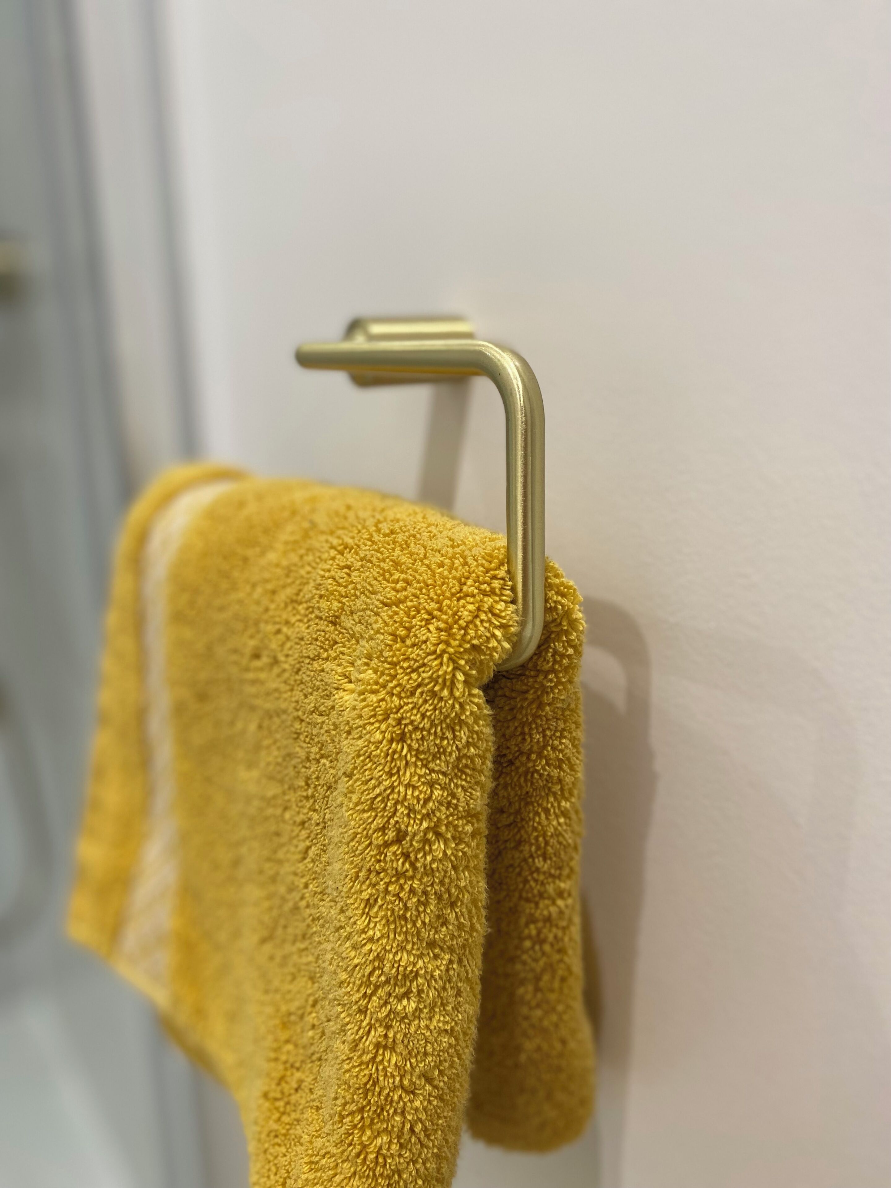 A yellow towel hanging on a metal towel rack.