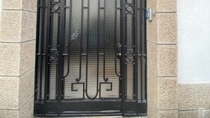 Un gran portón de metal ornamentado con diseños intrincados, enmarcado en un arco de piedra.
