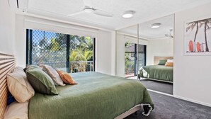 Un dormitorio con una cama grande, un ventilador de techo y vistas al exterior.