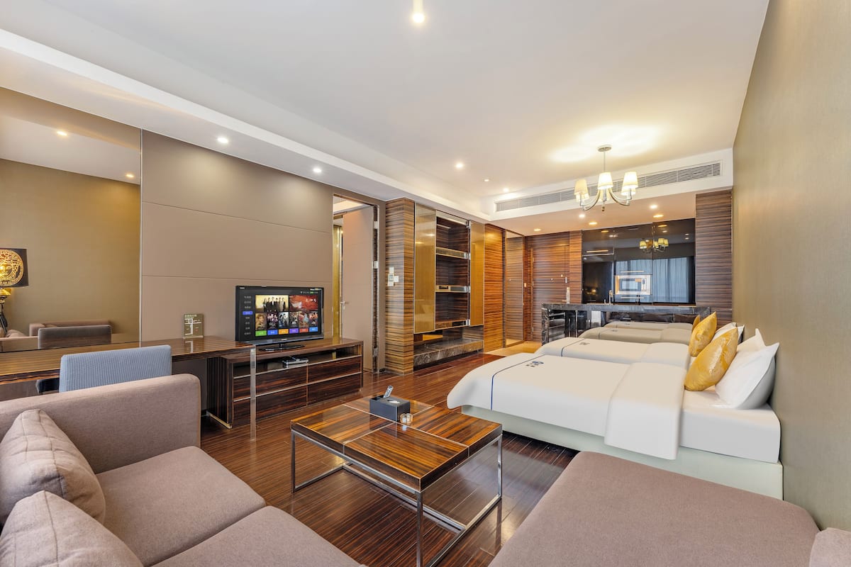 Habitación triple Deluxe | Área de sala de estar | Televisión de 65 pulgadas con canales por cable