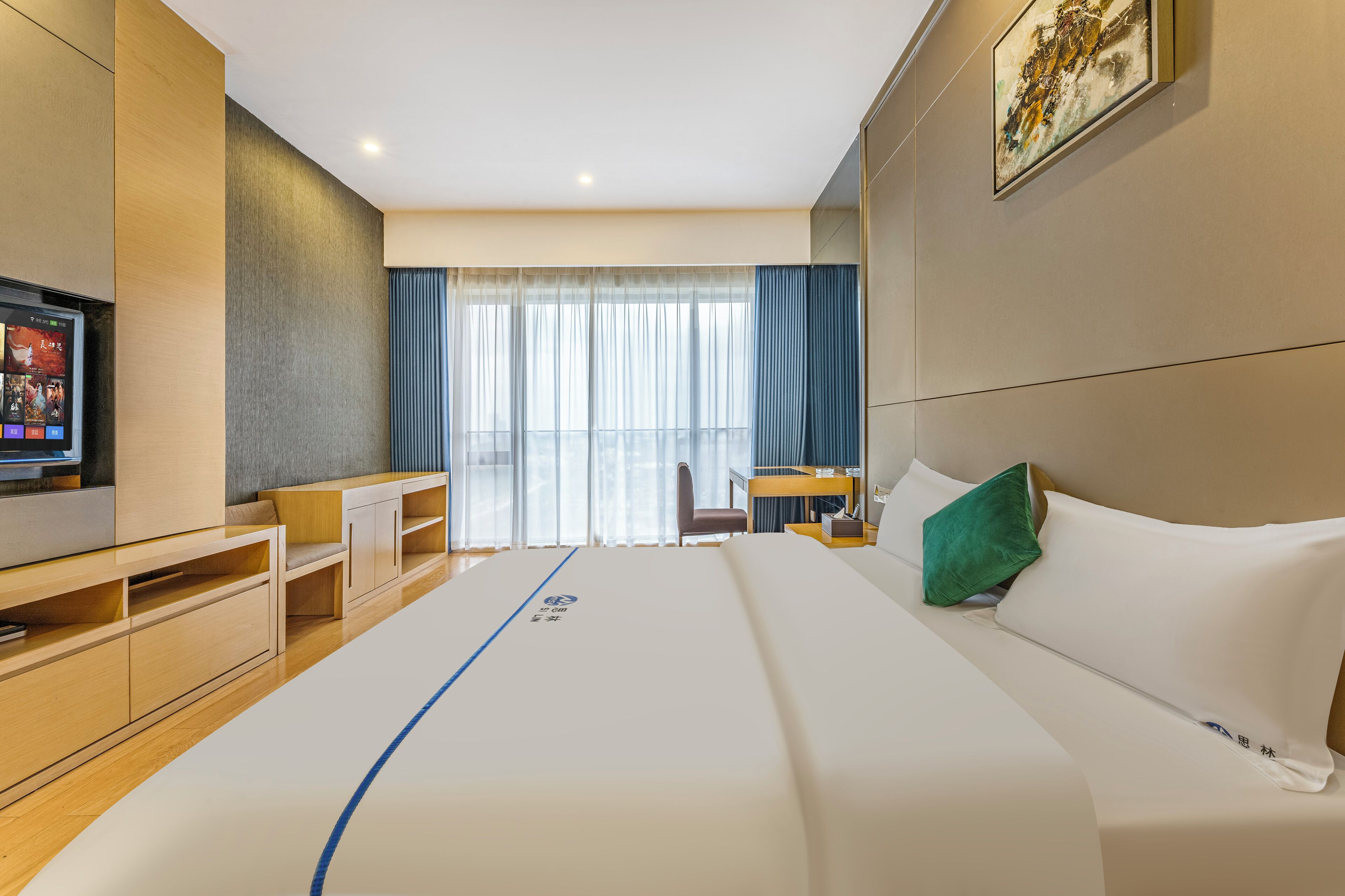 A modern hotel room with a large bed, a desk, and a television.