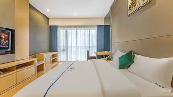 A modern hotel room with a large bed, a desk, and a television.