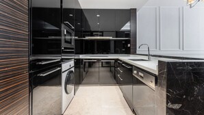A modern kitchen with a central island, built-in appliances, and a large sink. - Side Apartment (Guangzhou)
