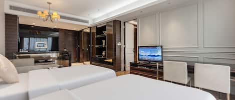 Habitación de hotel con dos camas, televisión, zona de comedor y kitchenette.