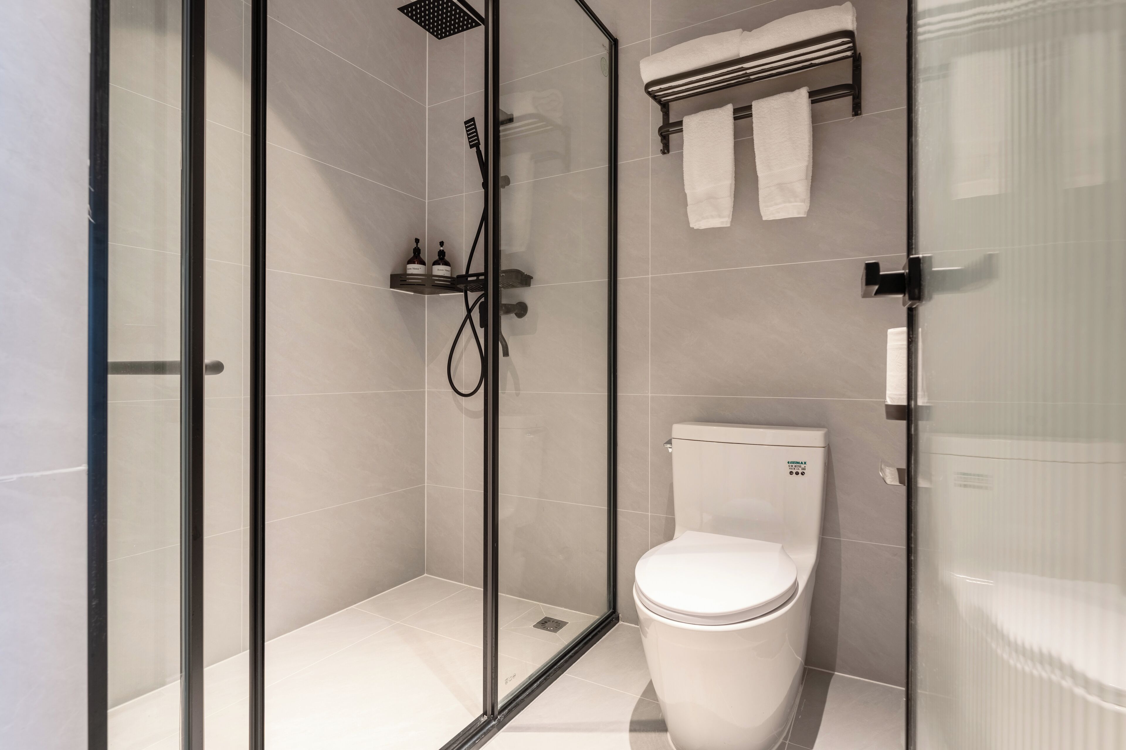 A modern bathroom with a glass-enclosed shower, a toilet, and a towel rack.