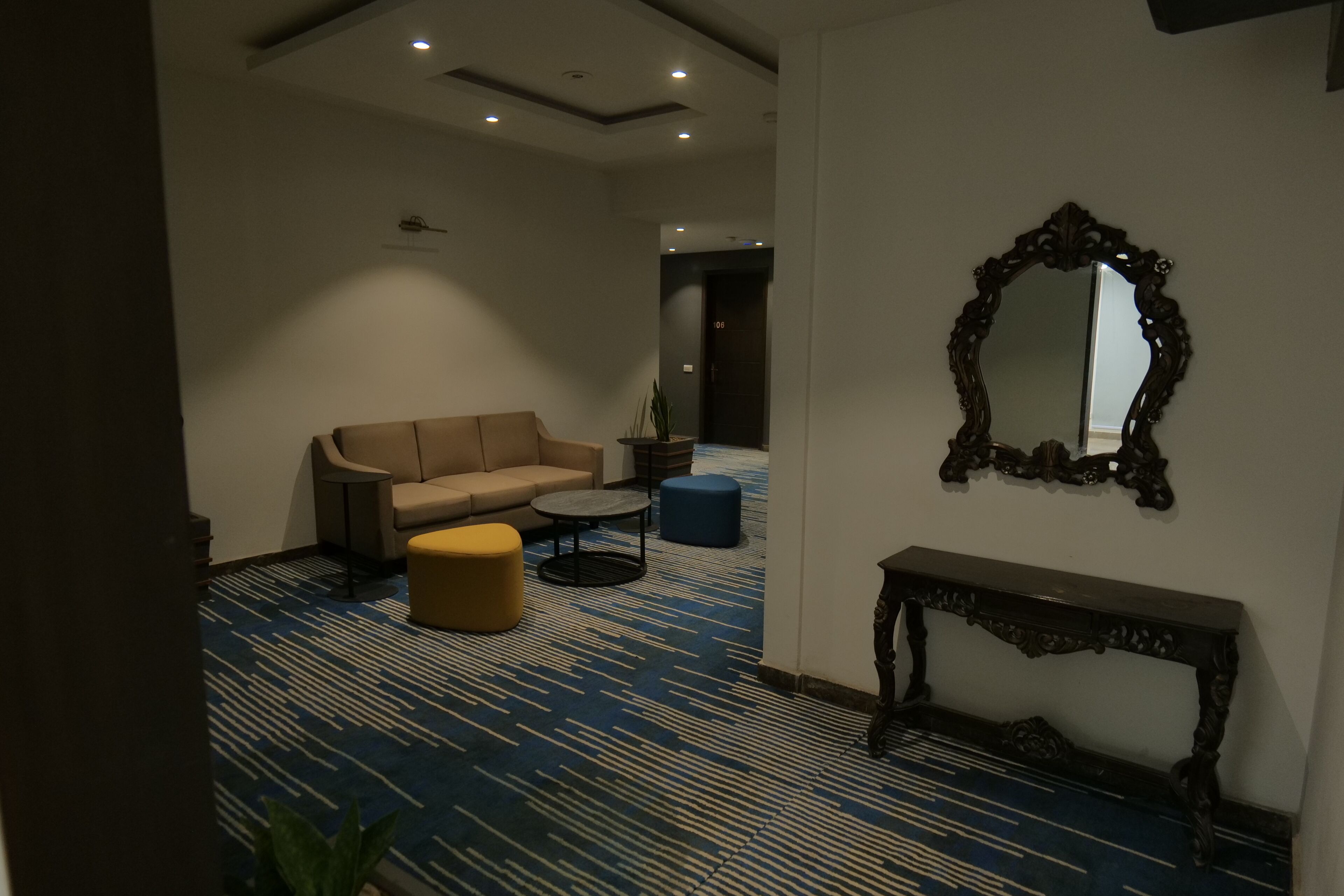 Een moderne hotellobby met een bank, voetenbankje, rond bijzettafeltje en een console.