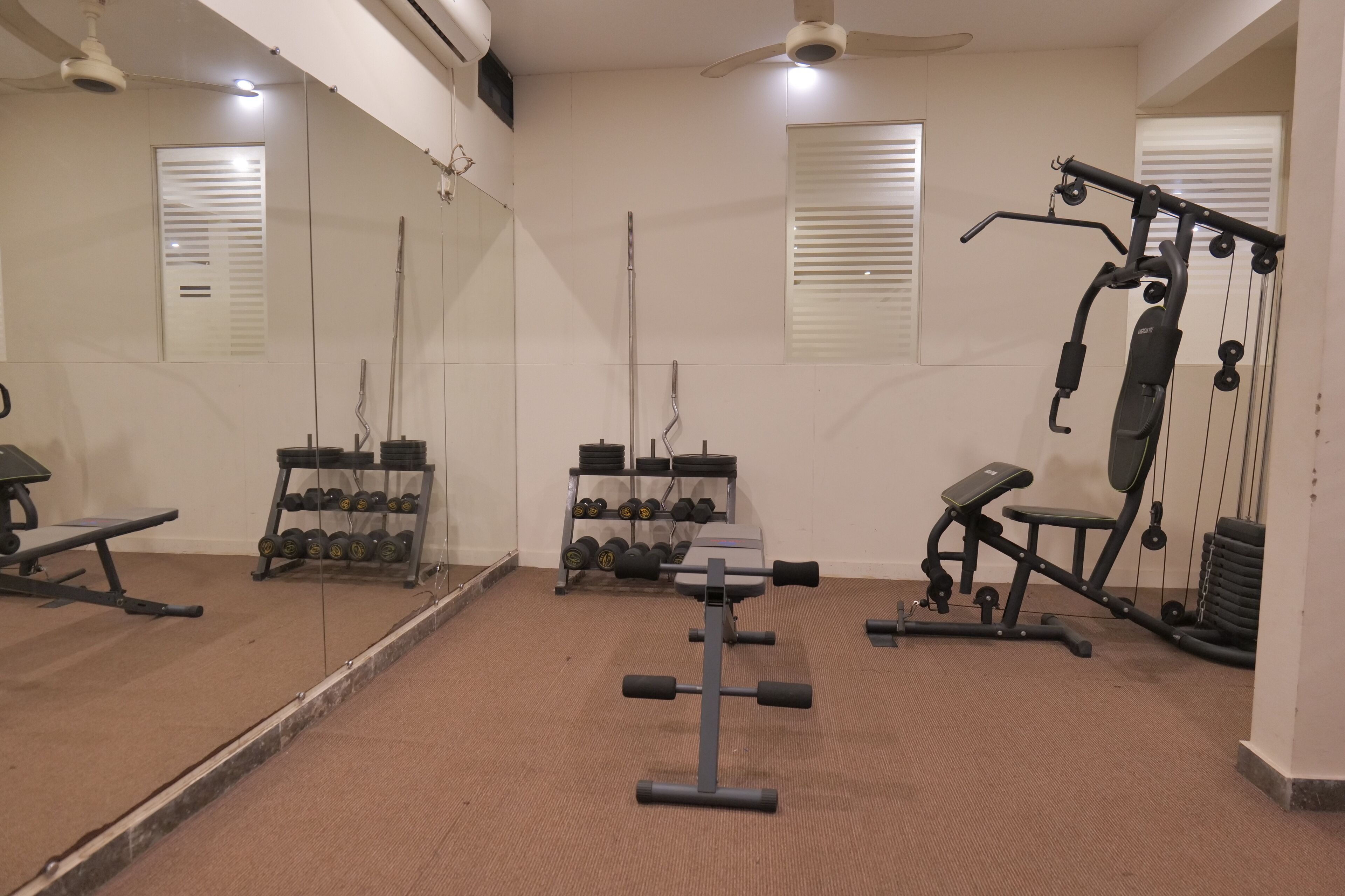 A gym with exercise equipment, mirrors, and a weight rack.