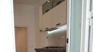 A modern kitchen with dark cabinets, a stainless steel range, and a window above the sink. - Mini Apartment With Bathroom and Kitchen (Portici)