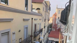 A narrow street between buildings with balconies, a red-roofed building, and a person walking. - Mini Apartment With Bathroom and Kitchen (Portici)