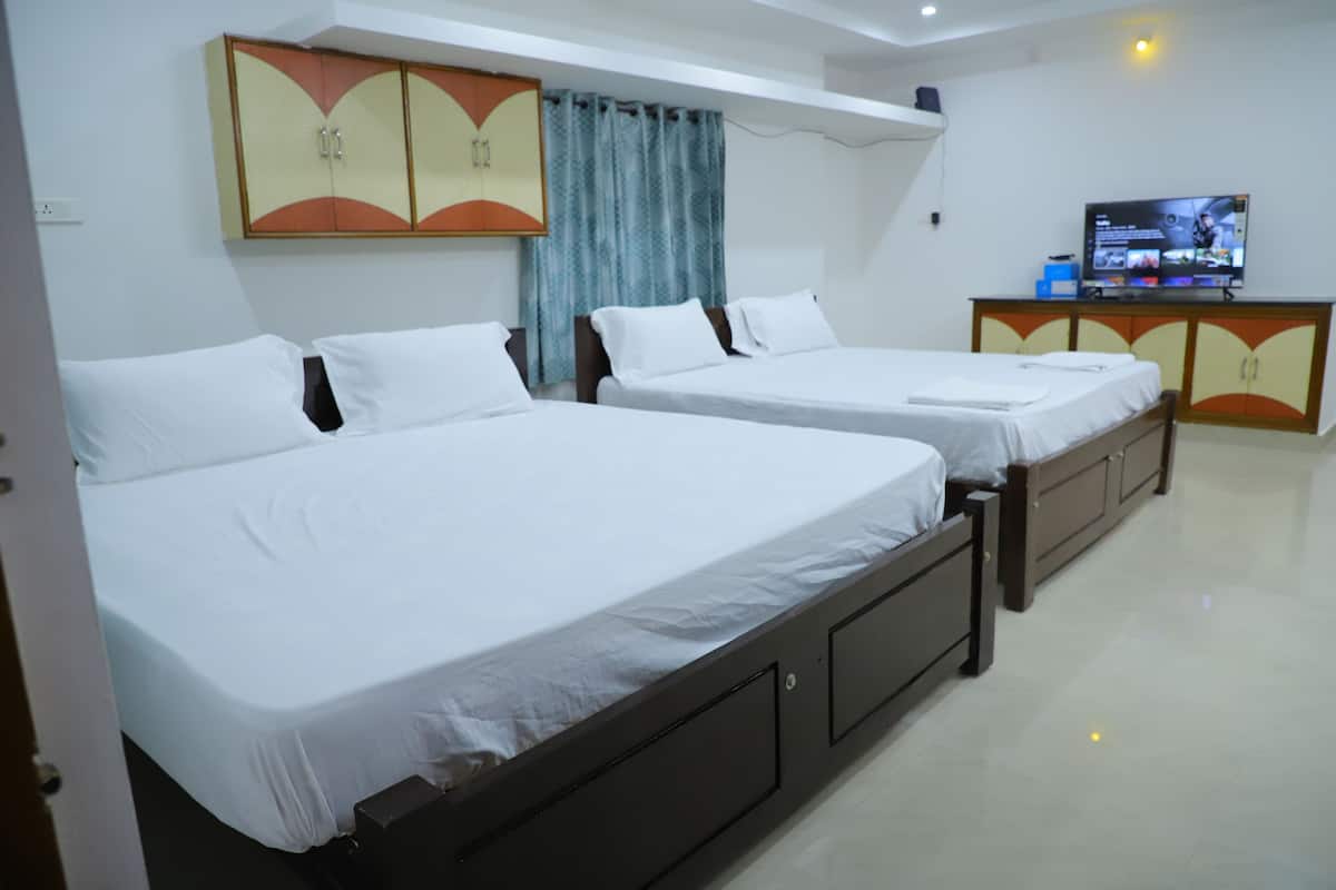 Quarto de hotel com duas camas de solteiro, uma televisão e um guarda-roupa.