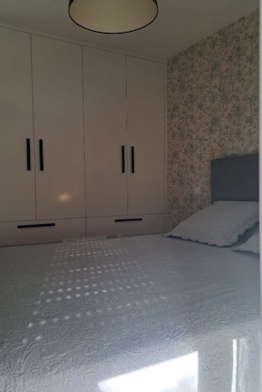 A bedroom with a bed, a wardrobe, and a floral wallpaper. - Le Gîte de "mam Goz" (Paimpol)