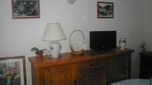 Una sala de estar con un aparador de madera, un televisor, una lámpara y dos cuadros en la pared.