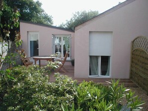 A pink building with a patio area, a table, and chairs.