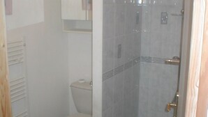 Un baño con inodoro, cabina de ducha y toallero.