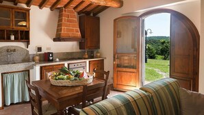 Une cuisine rustique avec un évier en pierre, des armoires en bois et une cheminée en briques.