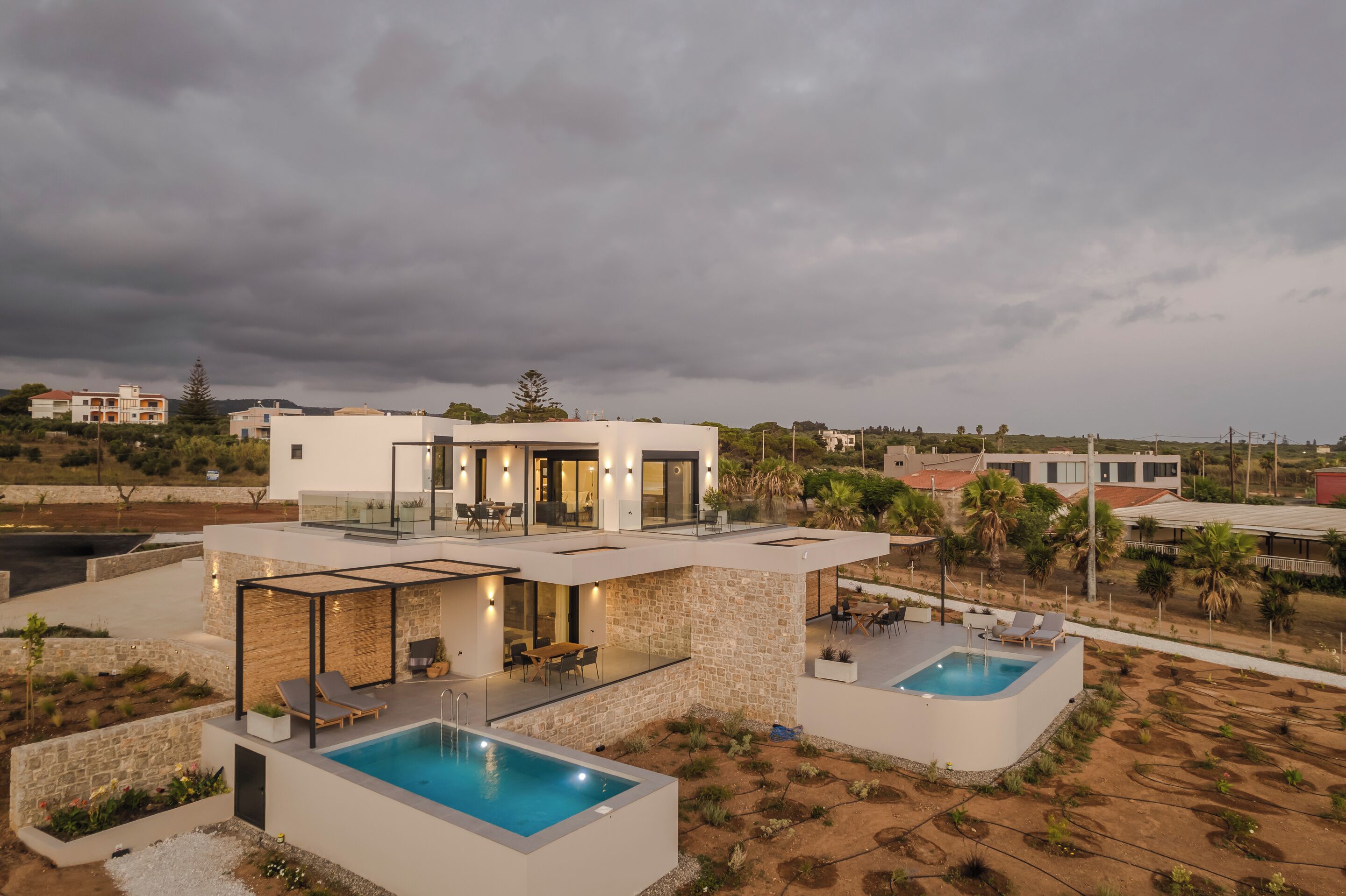A modern house with a pool, outdoor seating, and a stone facade.