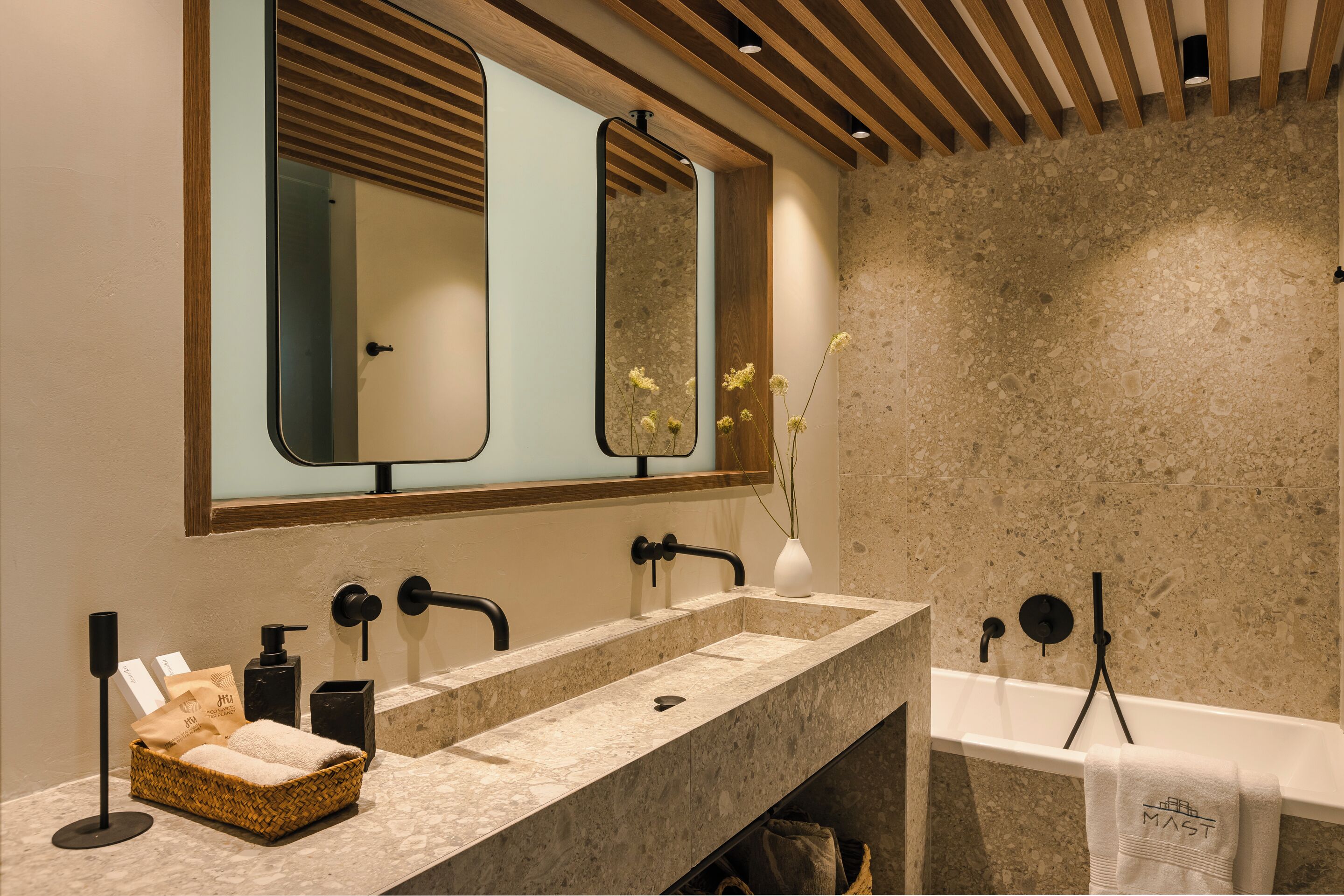 Un baño moderno con un espejo grande, un lavamanos y una bañera.