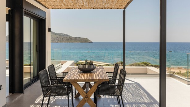 Una terraza con mesa y sillas, con vistas a la costa.