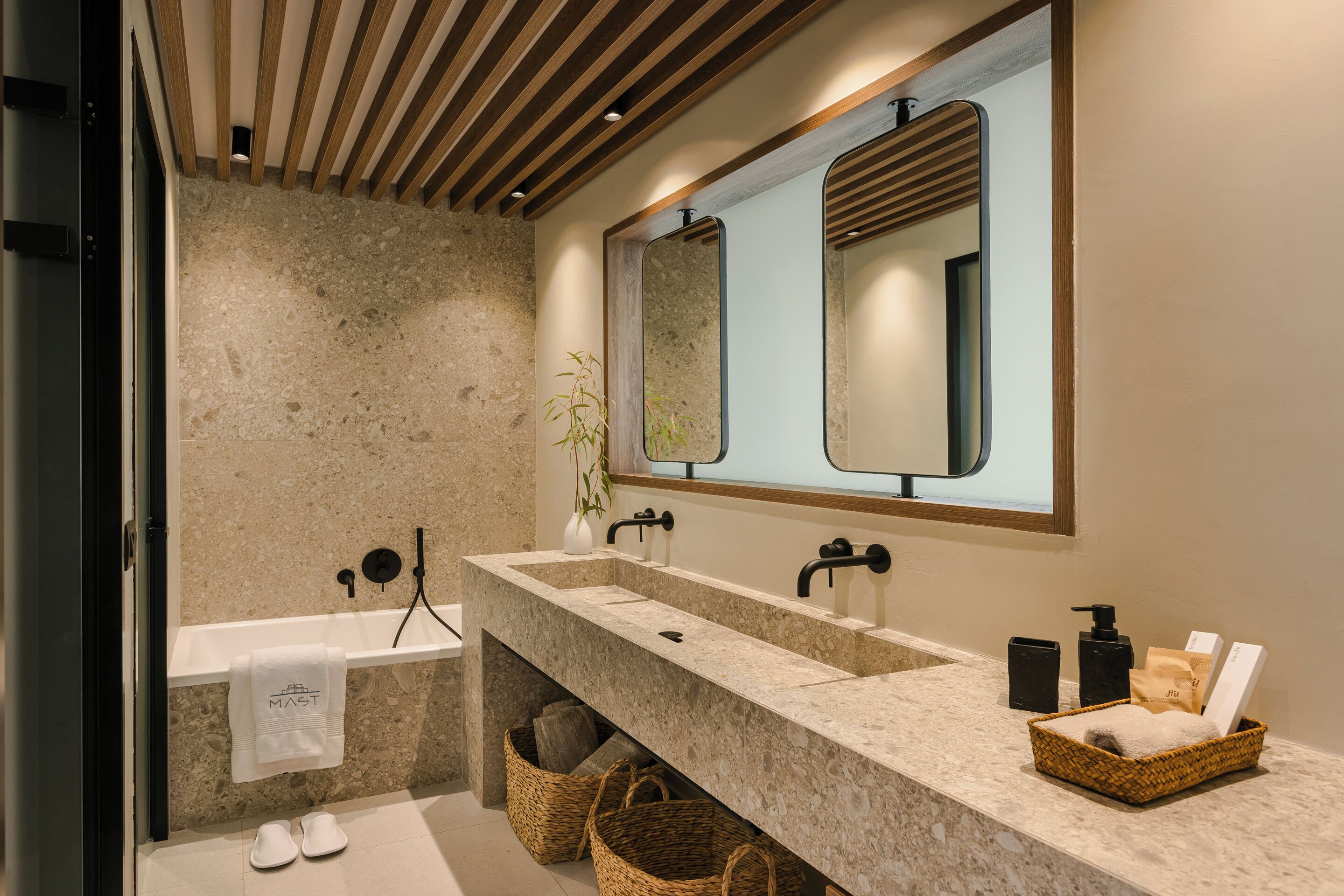 A modern bathroom with a stone countertop, dual sinks, a large mirror, and a towel rack.