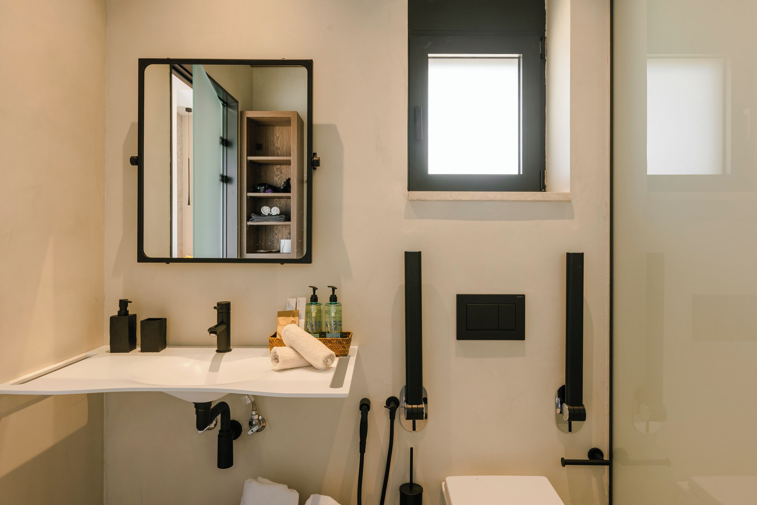 A modern bathroom with a white sink, a mirror, a towel, and a window.