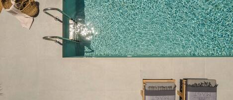 A swimming pool with clear water, a towel, and a hat on the edge.