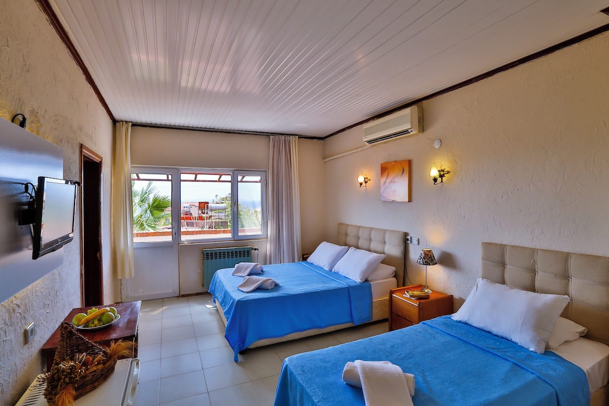 A hotel room with two beds, a TV, a window with curtains, and a view of the outside.