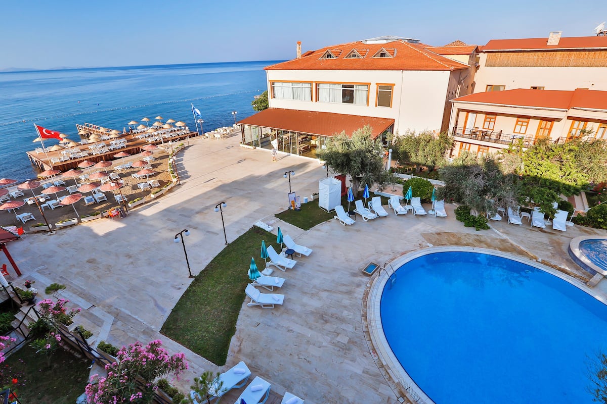 A resort with a swimming pool, sun loungers, and a view of the sea.