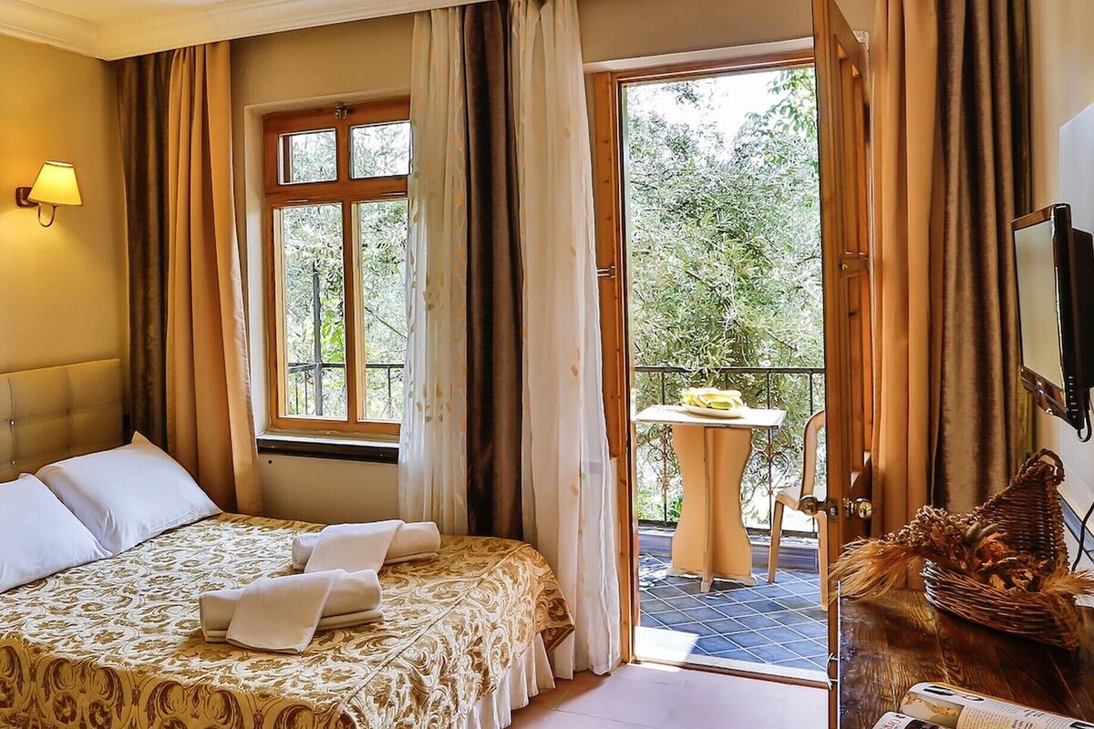 A hotel room with a bed, a TV, a balcony with a table, and a decorative basket.