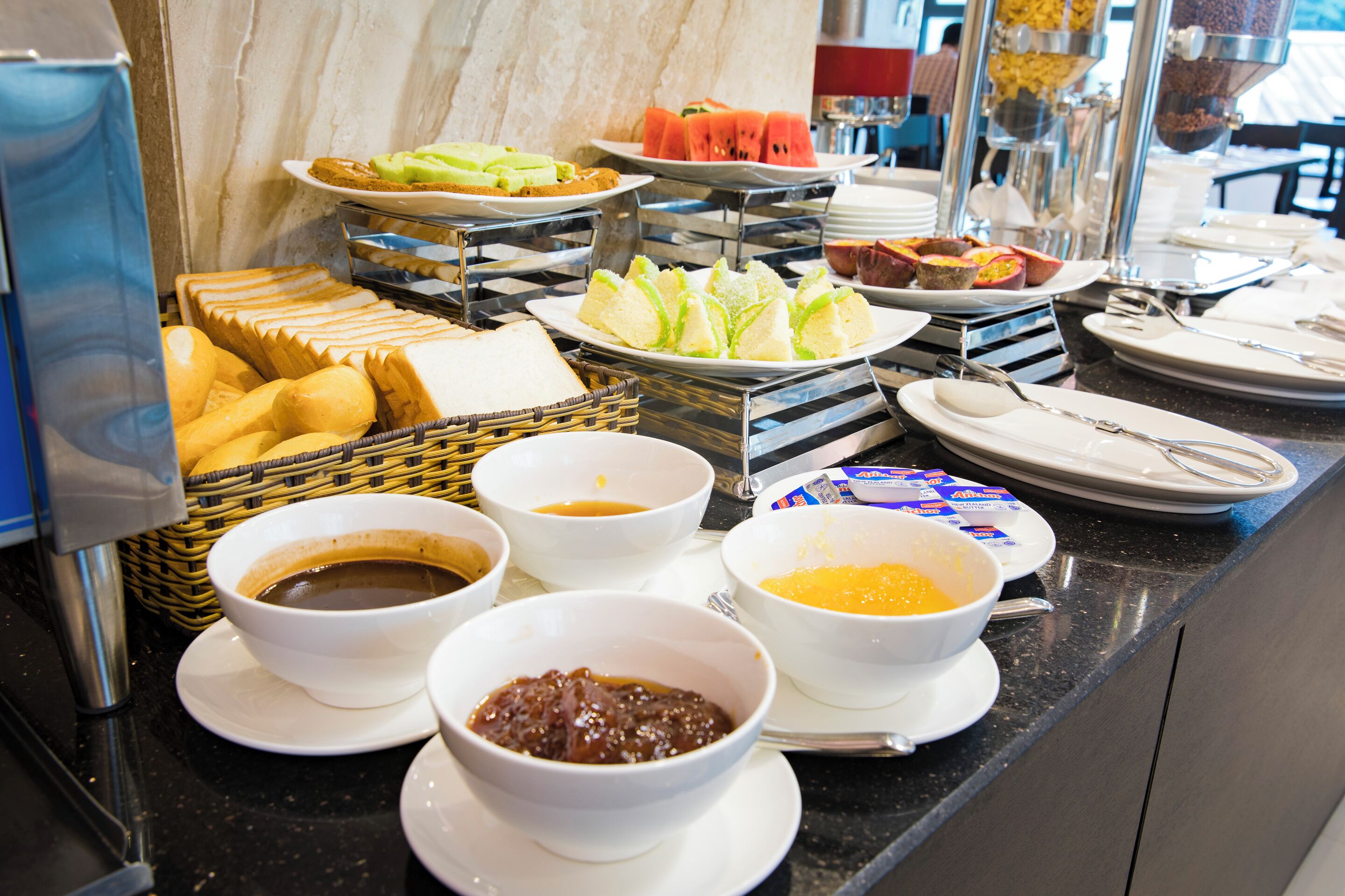 Un buffet proposant une variété d’aliments, notamment du pain, des fruits et des boissons.