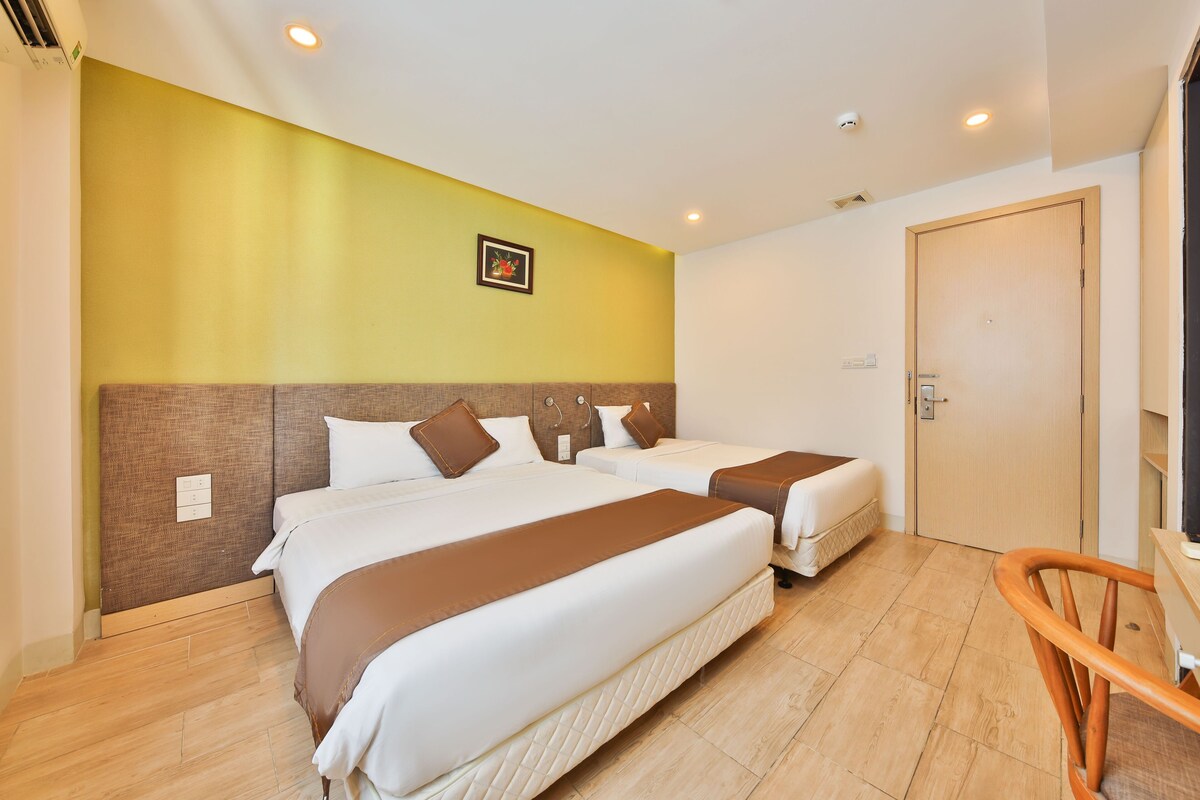 A hotel room with two beds, a wooden headboard, a wooden chair, and a door.