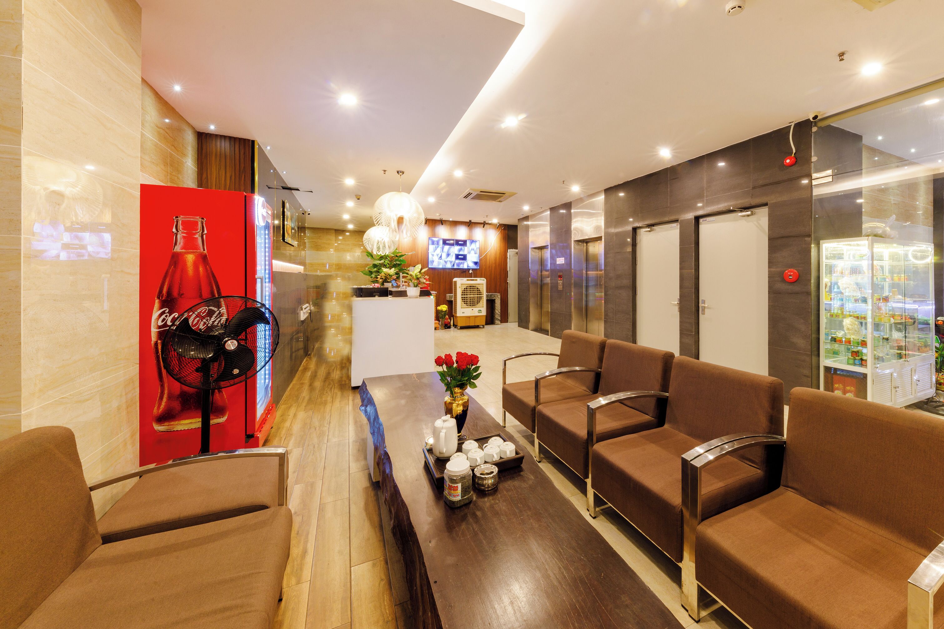 A modern hotel lobby with seating, a reception desk, and a vending machine.