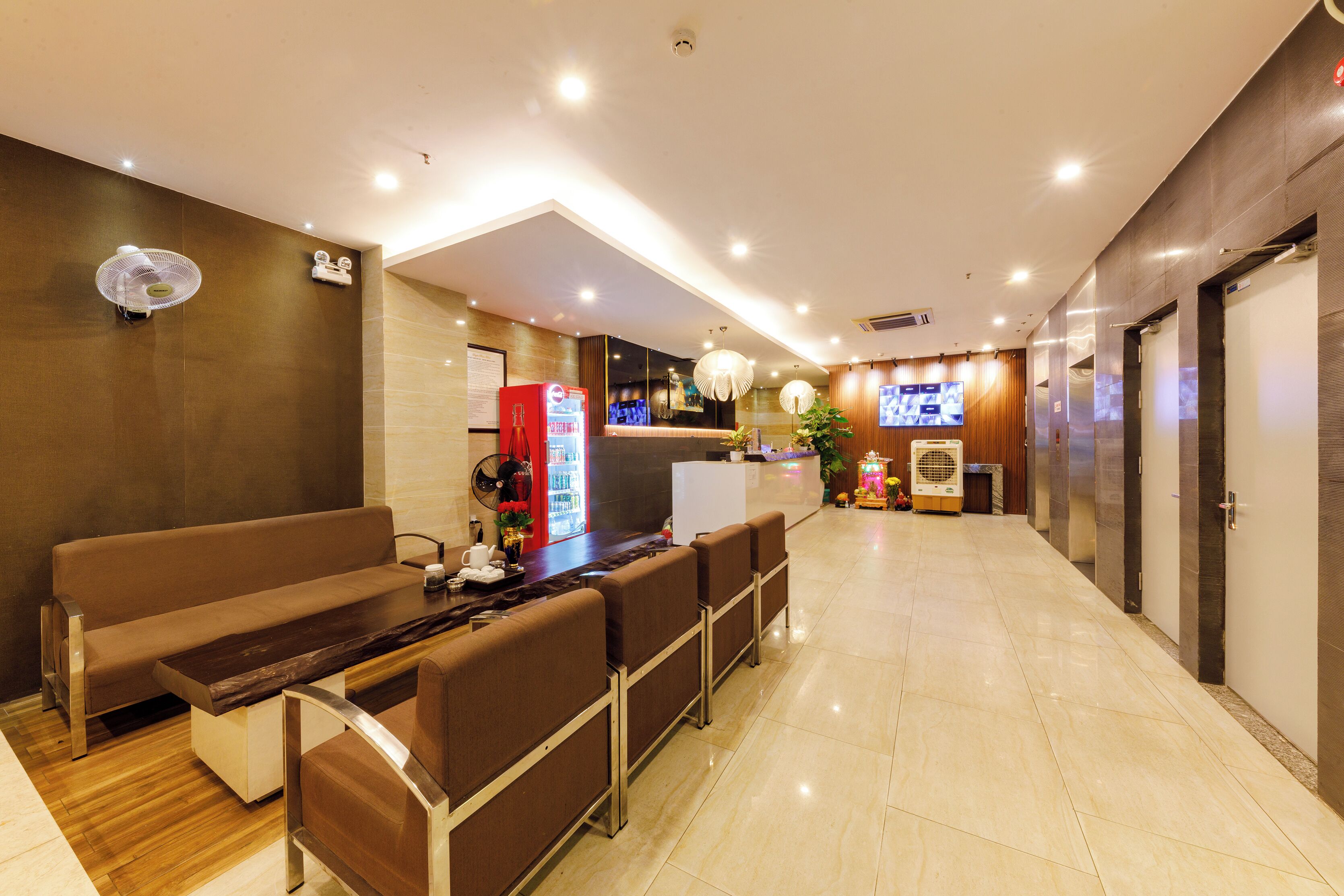 A modern hotel lobby with a reception desk, seating area, and a vending machine.