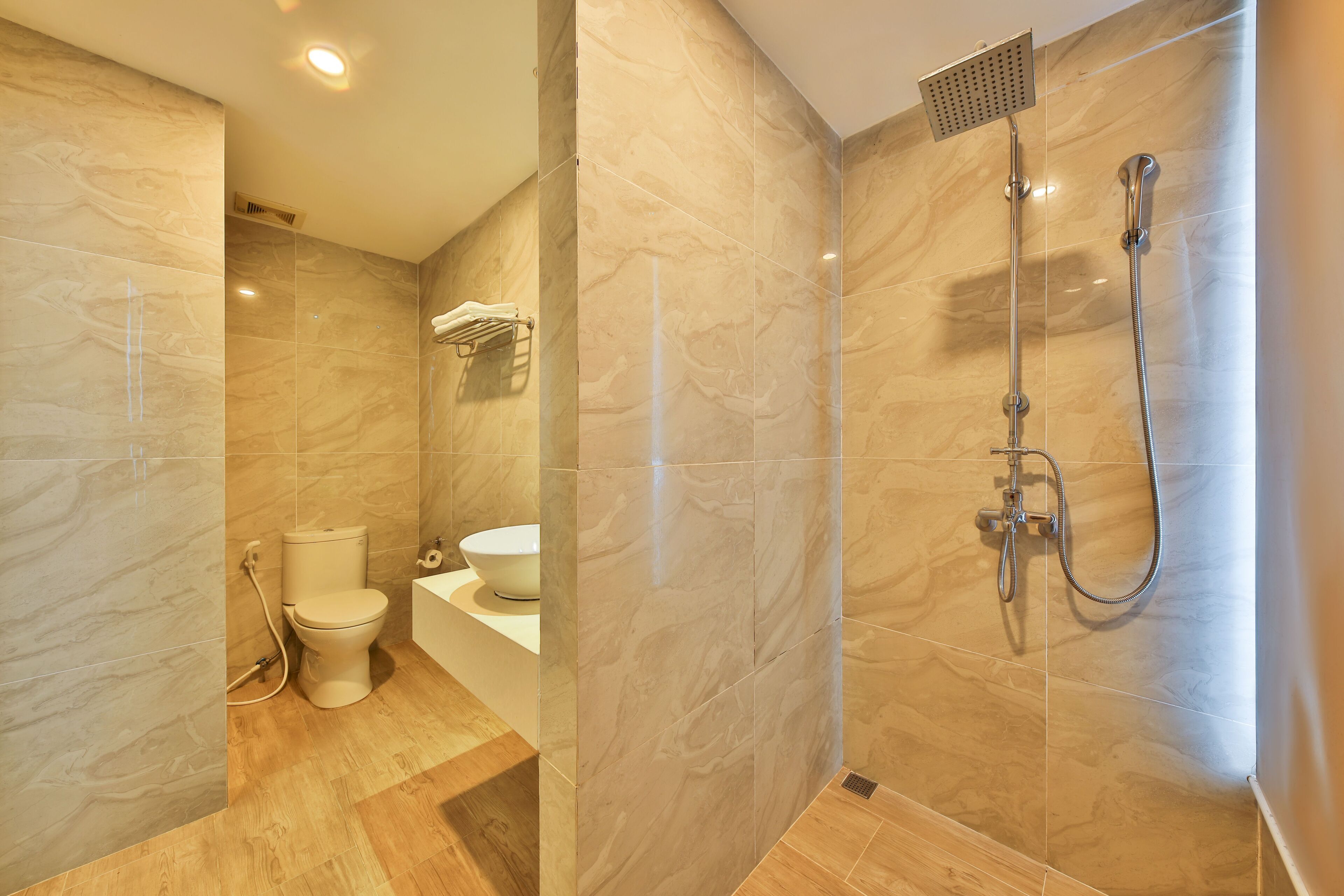 Un baño moderno con ducha de mármol, inodoro y lavabo.
